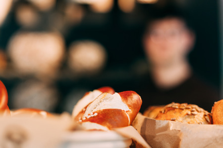 Bread rolls close-up in a bakery, the baker image blurredの写真素材