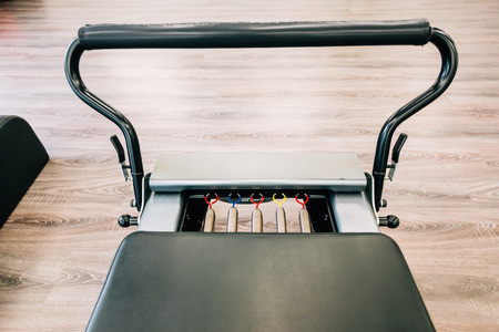 Pilates reformer close-up with focus on colored springs.
