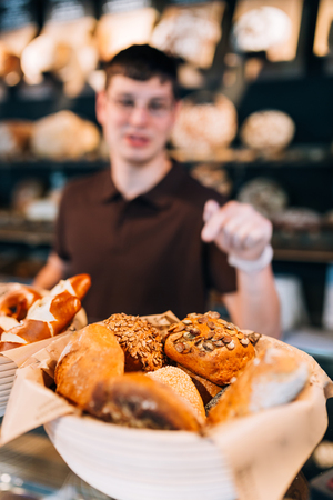Blurry pose of breadbasket full of buns and a salesman behind. Focus on the bunsの写真素材