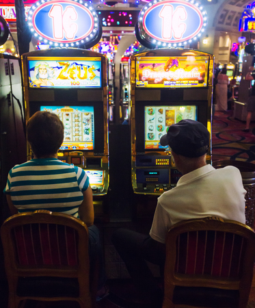LAS VEGAS, , NV, USA - JULY 13, 2013: Busy couple playing slot machines in a Hotel Casino.のeditorial素材