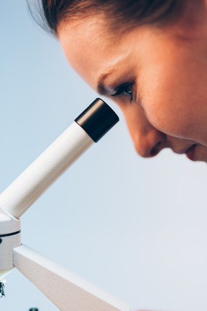 Young researcher looking through a medical microscopeの写真素材