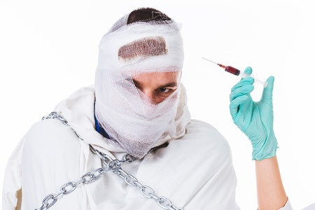 Young insane man with straitjacket and chains preparing for an injection - isolated on white.の写真素材