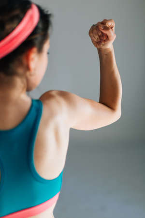 Profile od a fit woman flexing her arms muscles