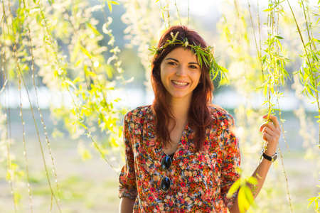 Front photo of beautiful woman smiling at camera while holding willow branchesの写真素材