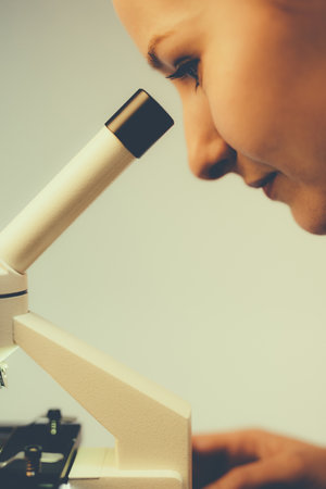 Scientific researcher using microscope and looking at sample in a laboratoryの写真素材