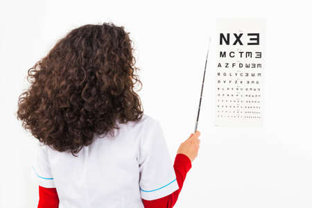 Ophtalmologist woman pointing at a letter on eye chart with a stick - isolated on white.の写真素材