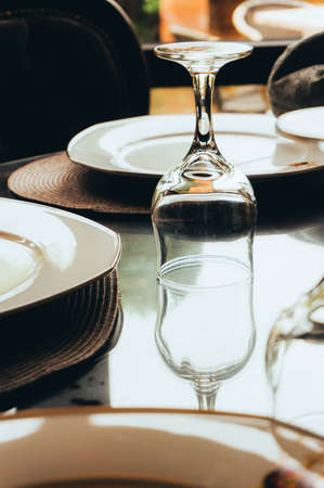 Close-up image of an empty glass upside down with it's reflection on the table