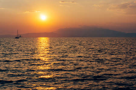 Beautiful photography of sun from the sea.The sun is shining and the rays color the water in orange.の写真素材