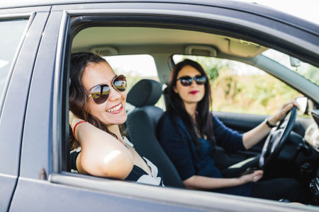 Pose of two women smiling to the camera and thinking about the car trip.の写真素材