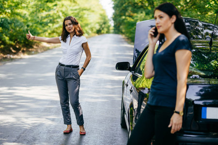 Two women stuck in a forest with a broken down car.の写真素材