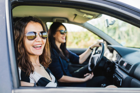 Profile pose of two young ladies are laughing while the eldest is driving.の写真素材
