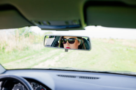 Reflection in the car's rear-view mirror of an elegant woman while drivingの写真素材