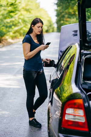 Young woman calling for help after the car broke-down by the side of the rodeの写真素材