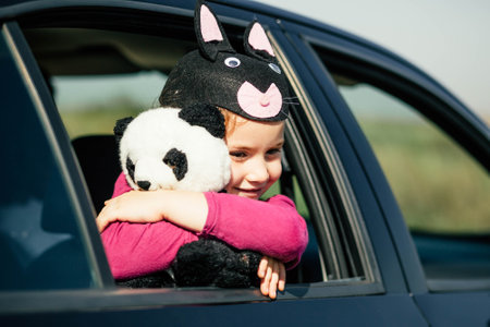 Pose of a beautiful and innocence little girl who is holding her teddy bear while she is in the car.の写真素材