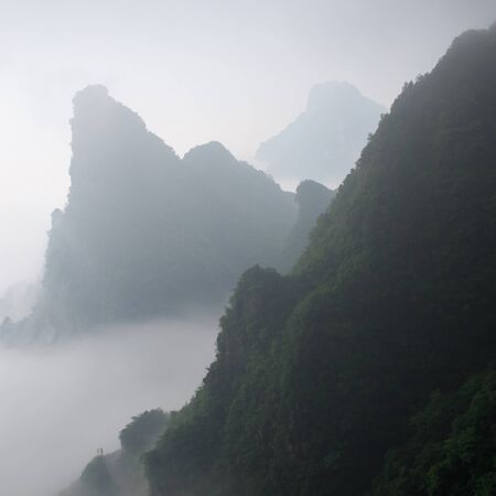 Photo of Huge Rock Mountain Silhouette with White Mist. Epic Mountain Landscapeの写真素材