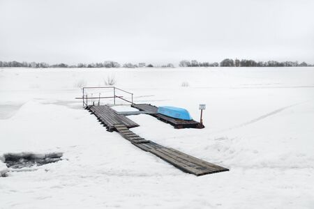 Boat on the pier with snow riverの写真素材