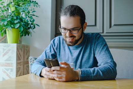 Young man in caffe with smartphone while business breakの写真素材