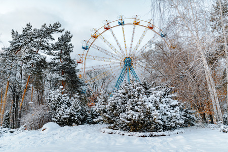 Ferris circle attraction in beautiful winter snow park with blue sky and treesの写真素材