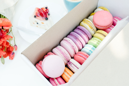Macaron dessert and tasty fruit cake on white wooden table. Poppy flower and cappuccino.の写真素材
