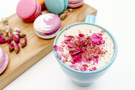 French beautiful macarons on wood desk and blue cup of aroma cappuccino on white tableの写真素材