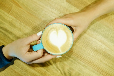 Human feelings. Frothy cappuccino between two hands. Friendship pastime.の写真素材