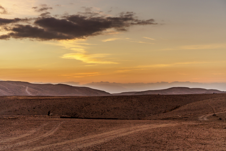 Colorful landscape view on sunrise in middle east. Negev desert in Israel with amazing red morning sky, yellow sun and mountains, sand cliffs. Scenery orange warm sunlight and cloudy background.の写真素材