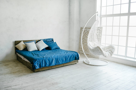 Minimalistic interior with white walls and modern bed. Big windows apartment. Comfortable and elegantの写真素材