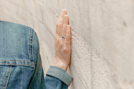 White woman hand touches the wall. Closeup of religion fingers on the stone ancient street wall. Ritual and feelings of prayer person beside the exterior constructionの写真素材