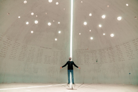 Puzzles of astronomy. Rear view of young unidentified man in casual clothes stands in the center of the planetarium and examine the ancient domeの写真素材