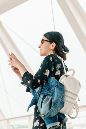 Tourist concept. Young positive woman in casual clothes and sunglasses makes selfie on the background of attractions while travelingの写真素材