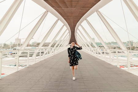 Tourist concept. Young woman in casual clothes with bag standing on the open balcony of large building and admiring the viewの写真素材