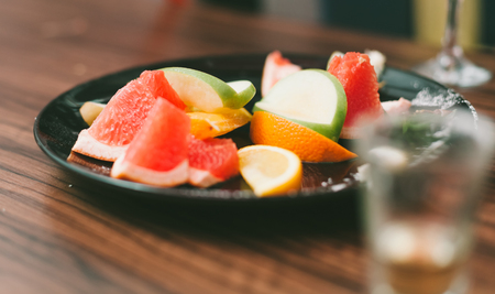 Orange slices, Apple slices, grapefruit segments on the black plate.の写真素材