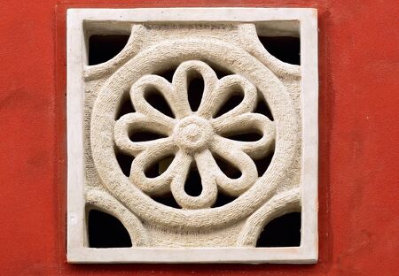 Old stone ornament on the red wall