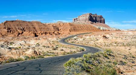 A simple paved road winds through a rocky desert landscape.の写真素材