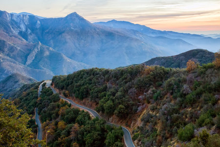 A curvy two-lane road winds it way around a mountain at sunset. Taken at Sequoia National Park in California.の写真素材