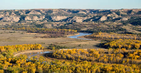 A river winds through fall-colored trees at Theodore Roosevelt National Park in North Dakota.の写真素材
