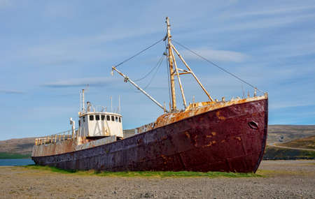 An old rusted steel shipwreck sits on an Icelandic beach.の写真素材
