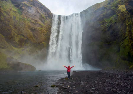 A happy female tourist at SkÃ³gafoss waterfall in Iceland.の写真素材