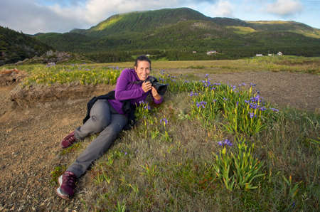 A female photographer shooting blue flag irises (iris versicolor) in scenic Newfoundland.の写真素材