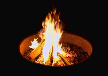 A campfire in a simple firepit burning brightly at night.