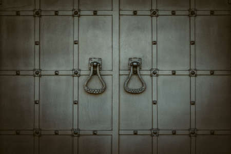Vintage metal gray door. Closed antique gate with forged steel handles. Blocked entrance. Durable protection conceptの写真素材