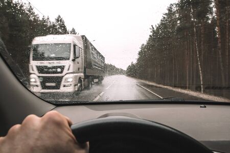 View through windshield of wet rainy inclement weather and highway with truck in oncoming lane. Danger of cars moving in rainの写真素材