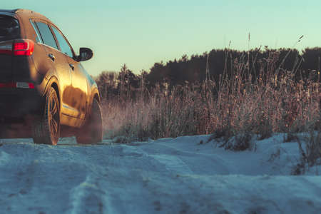 Car with winter tires and tyre trail on winter rough road in snow season.