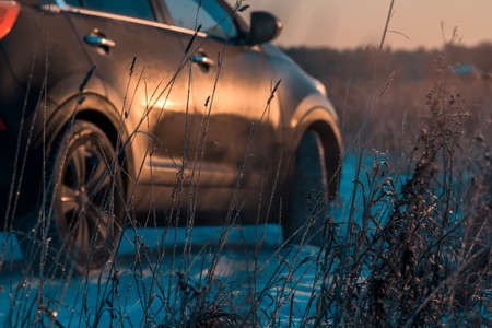 Car stuck in snowdrift on slippery road in dark rural area.の写真素材