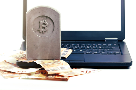 stone monument/tombstone with bitcoin symbol standing on a pile of banknotes and a black notebook -composition in bright matte/chrome look on white backgroundの写真素材