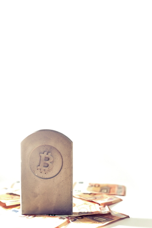stone monument/tombstone with bitcoin symbol on a pile of banknotes on white background - portrait composition in bright matte/chrome look with copy space for textの写真素材