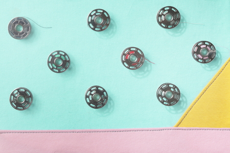 Collage of metal bobbin spools on seamed fabrics in pastel tones - trendy decoration with flat shadowsの写真素材