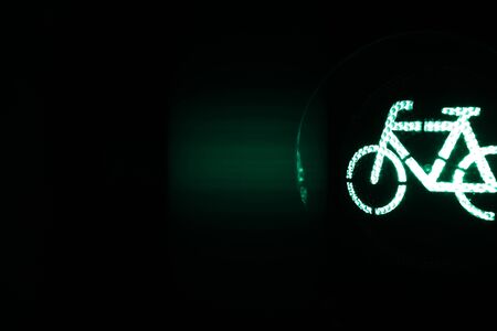 closeup on traffic light showing green bicycle symbol at night - dark surrounding with copy space...