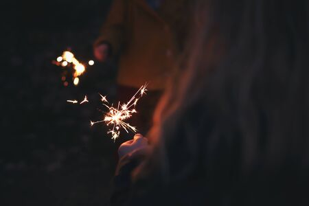 Two kids holding sparklers in twilight on a cold new year's eve - background and foreground blanked out blurryの写真素材