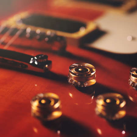 control panel of an electric guitar in transparent cherry sunburst with golden knobs - selective focus with background and foreground blanked out blurryの写真素材